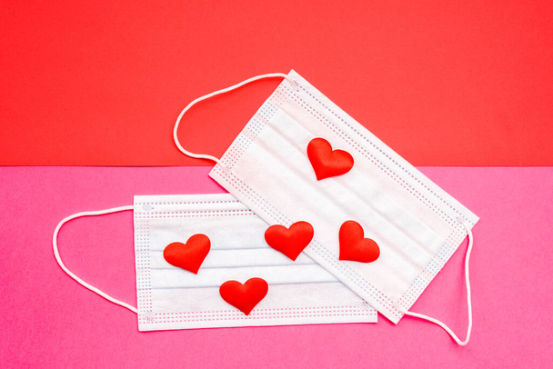 Flat lay of red love hearts on sanitary masks isolated on colored geometric backgrounds. - Фото, зображення