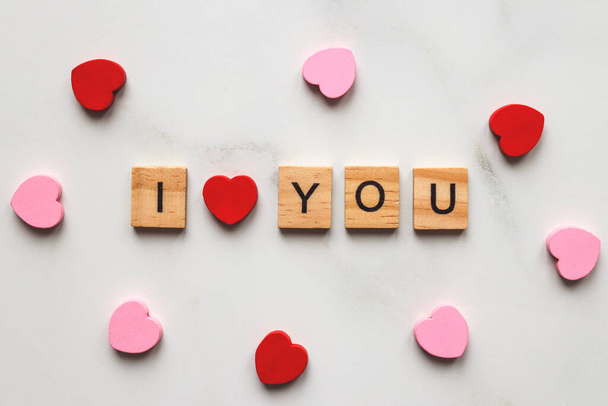 The inscription I love you made from wooden letters and little hearts on a marble background. Valentine's Day and love concept. - Fotografie, Obrázek