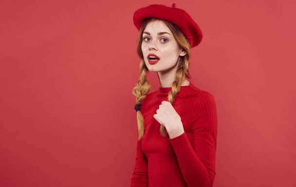 hezká žena v červených šatech čepice pigtails červené pozadí - Fotografie, Obrázek