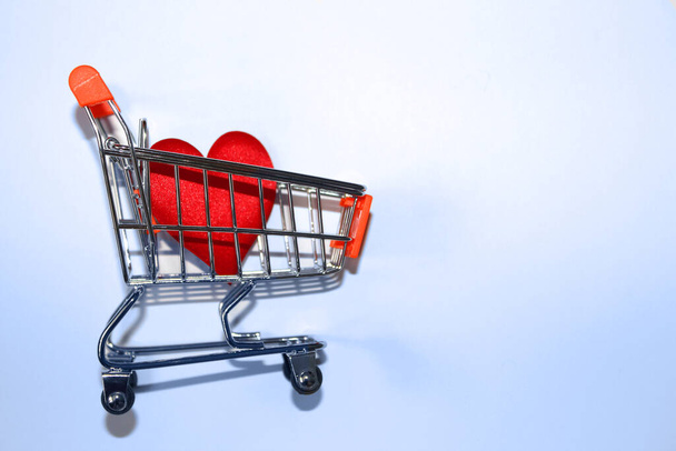 Red heart in shopping cart over white - Φωτογραφία, εικόνα