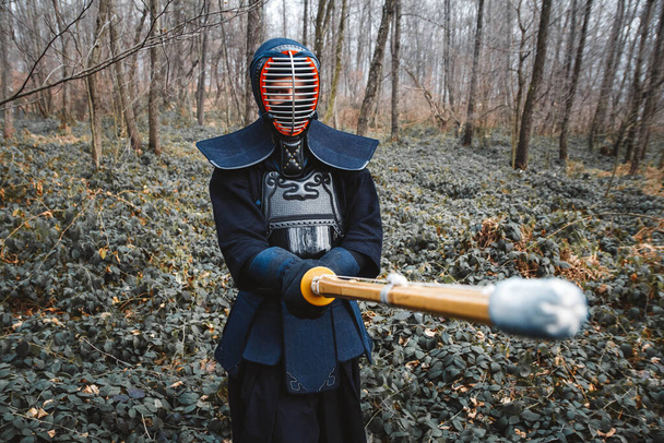 Человек, практикующий кэндо с бамбуковым мечом синай на фоне леса. Место для текста или рекламы. - Фото, изображение