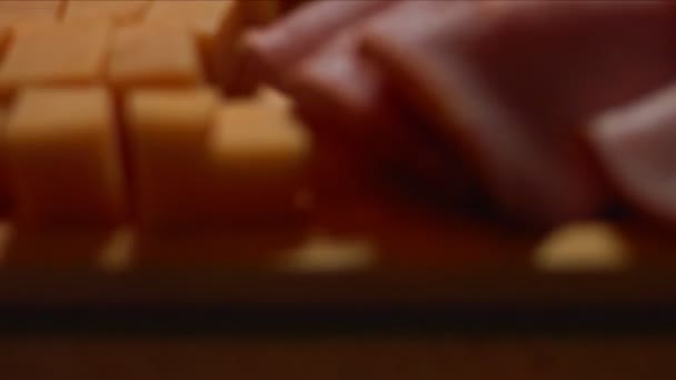 Nozes gregas sendo organizadas em uma bandeja de madeira com mel, cubos de queijo cheddar e fatias de presunto de porco como aperitivo saboroso e atraente. Vídeo 4K - Filmagem, Vídeo