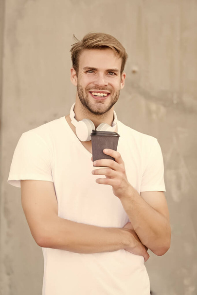He loves coffee. Modern man drink coffee in morning. Handsome man hold takeaway cup. Happy man in casual style. Caucasian man with unshaven face wear headphones. Single or bachelor. Fashion and style - Photo, image