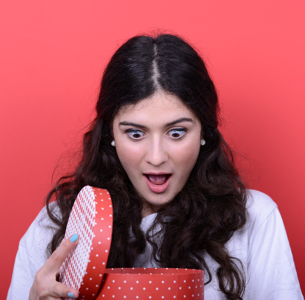 Portrait of happy woman opening gift box against red background - Foto, Imagen