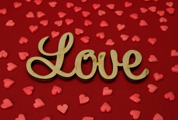 Wooden inscription Love hearts around on a red background - Fotografie, Obrázek