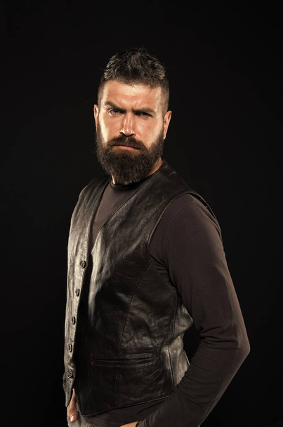 Man confident and brutal style black background. Handsome face. Man with beard in black leather clothes. Barbershop concept. Grow mustache. Fashion model. Strict mature face. Facial hair. Male face - Photo, image