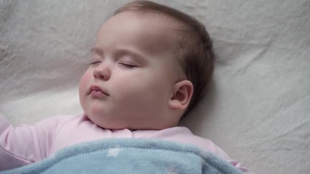 幼児、リラクゼーション、甘い夢、小児、家族のコンセプト-小さな9-12ヶ月のタイトアップ顔新生児の子供の女の子ランチタイム睡眠モードで毛布に覆われた白いベッドで寝る - 映像、動画