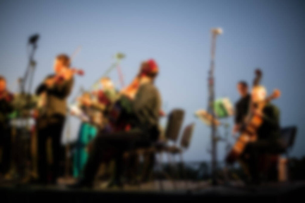 Background for design, blur texture, actors on stage scene in concert with silhouettes of people. De focused, Blurred image of the conductor introducing musical composition before performance.  - Photo, Image