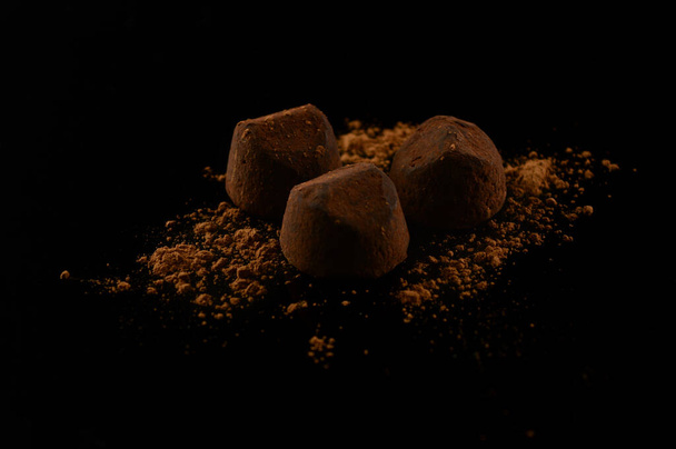 A group of three fine quality chocolate truffles over a black background. - Фото, изображение