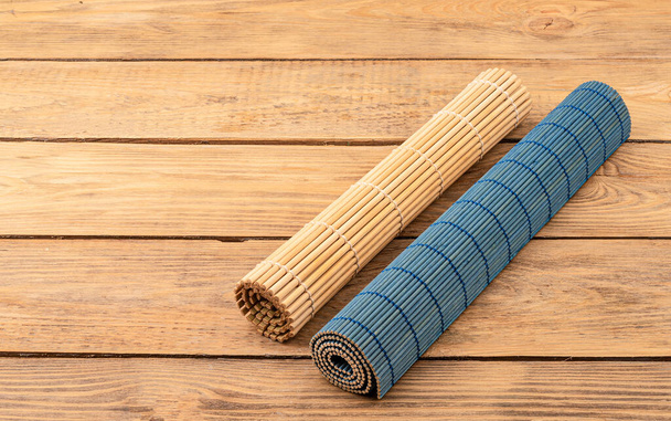 Two rolled up bamboo food mats on a wooden background. Copy space. Traditional kitchen utensils. - 写真・画像