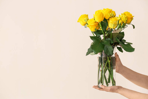 Hands with beautiful yellow roses on light background - Фото, изображение