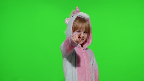 Маленькая девочка улыбается, указывает на камеру, делает жест с оружием руками в пижаме единорога - Кадры, видео
