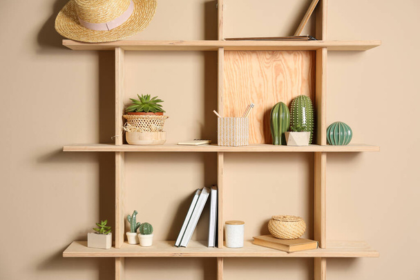 Wooden shelves with different decorative elements on beige wall - Fotoğraf, Görsel