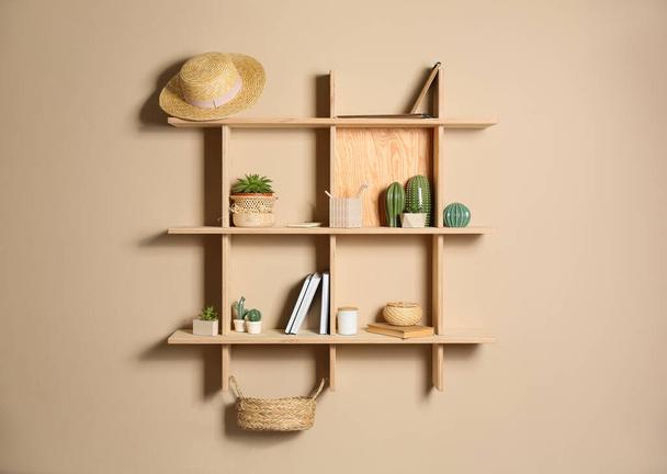 Wooden shelves with different decorative elements on beige wall - Fotografie, Obrázek