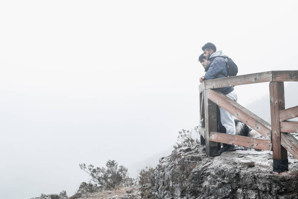 los excursionistas posan al borde de una montaña brumosa. - Foto, Imagen