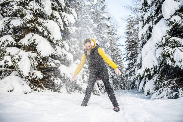 Schöne Frau in Ohrenschützer wirft Schnee an einem wunderschönen Wintertag. Berg, Winterlandschaft. - Foto, Bild