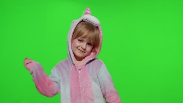 Μικρό ξανθό κοριτσάκι χαμογελά, χορεύει, γιορτάζει με στολή μονόκερου πιτζάμες στο κλειδί chroma - Πλάνα, βίντεο