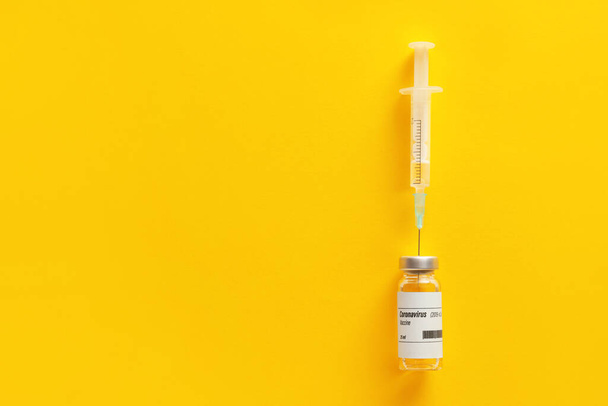 Вакцин для імунізації проти COVID-19 і шприц на кольоровому тлі - Фото, зображення