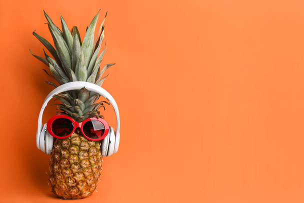 Pineapple with sunglasses and headphones on orange background, space for text. Creative concept - Foto, imagen
