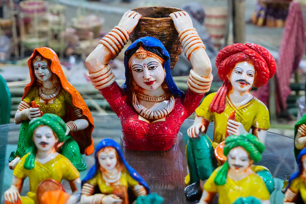 伝統的なインドのドレスを身に着けているカラフルな女性テラコッタ人形、彼女の背中に大きなバスケットを運ぶ、クリシュナガル、ナディア、西ベンガル州で作られた、コルカタでの手工芸品フェア中に販売のために表示. - 写真・画像
