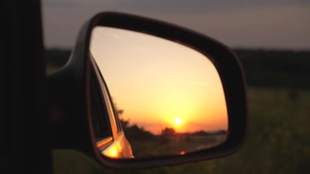 Een prachtige zonsondergang wordt weerspiegeld in de spiegel van de auto. het concept van avontuur en reizen. reizen met de auto buiten de stad. familie reis naar de natuur in een weekend - Video