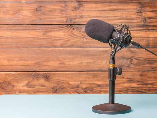 Debout avec un microphone moderne sur une table bleue sur un fond en bois. Appareils d'enregistrement sonore. - Photo, image