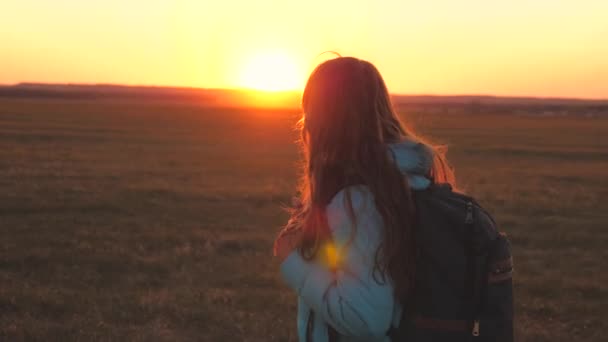 Ein Mädchen geht mit einem Rucksack auf dem Rücken spazieren und lächelt den Sonnenuntergang am Himmel an. Ein Teenager auf einem Campingausflug im Urlaub. Kindheit auf der Suche nach Abenteuer von morgens bis abends. Liebe für die - Filmmaterial, Video