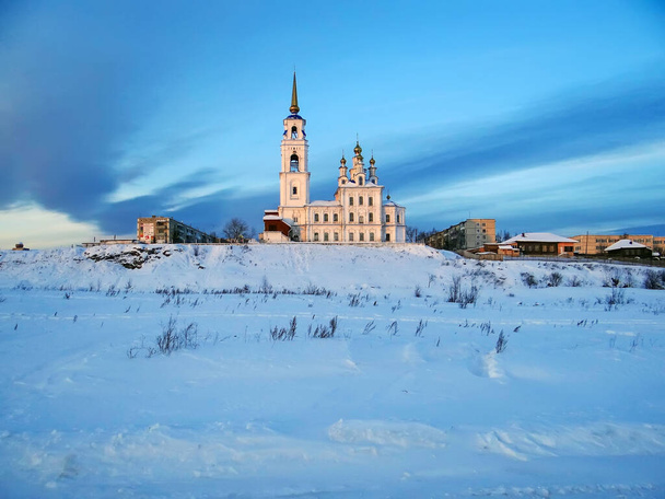 Szent apostolok temploma Péter és Pavel és falusi házak havas jelenetben - Fotó, kép