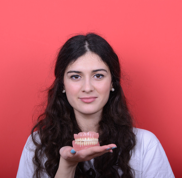 Portrait of happy woman with healthy smile holding denture again - Foto, Bild