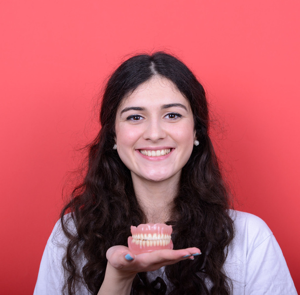 Portrait of happy woman with healthy smile holding denture again - Foto, imagen