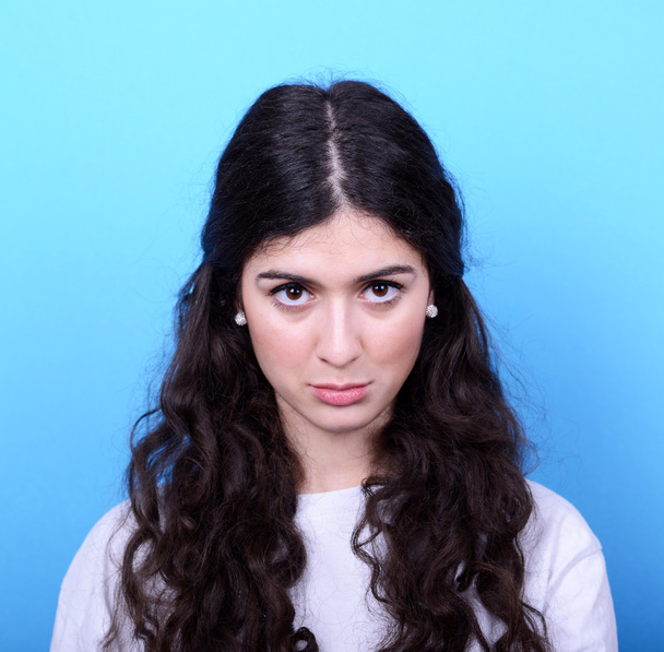 Portrait of sad girl against blue background - Foto, imagen