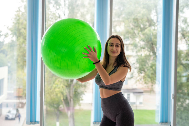 Όμορφη λεπτή γυναίκα στο αθλητικό ντύσιμο κάνει άσκηση στο γυμναστήριο χρησιμοποιώντας fitball. τρόπος ζωής - Φωτογραφία, εικόνα