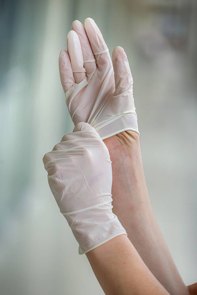 Kadın doktor, klinikte sıkı çalışma gününden önce koruyucu ameliyat eldivenleri giyer. Covid19 'dan güvenlik - Fotoğraf, Görsel