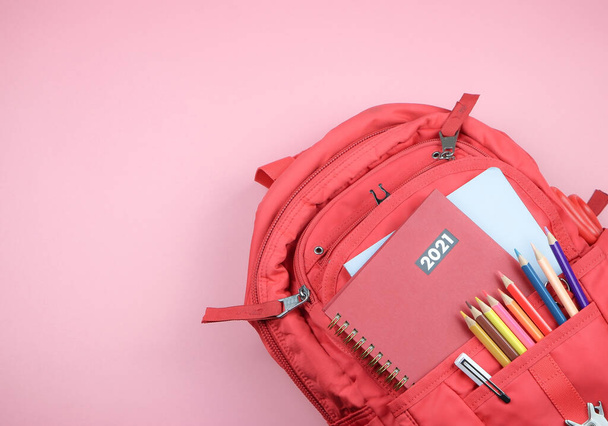 Вид зверху на червоний щоденник 2021 року в рюкзаку з шкільними приладдям на рожевому тлі з копіювальним простором. до школи в 2021 році
 . - Фото, зображення