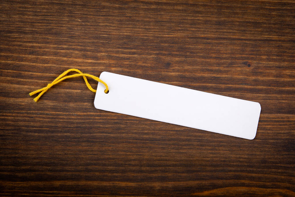 Paper price tag with yellow cord on a wooden texture background - Фото, зображення