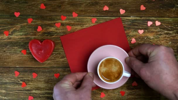 As mãos humanas colocam xícara de café no guardanapo vermelho e acendem a vela em forma de coração. Um dia romântico. Dia dos Namorados ou conceito do dia das mulheres. Vista superior. Deitado. Close-up. - Filmagem, Vídeo