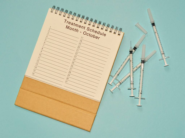 October treatment schedule calendar and disposable injection syringe - Photo, Image