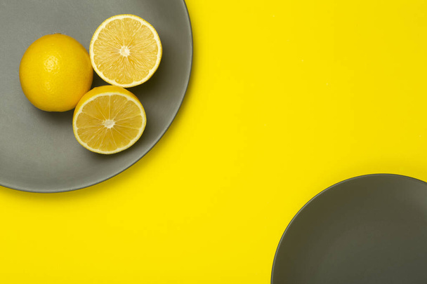 Osvětlující žlutý citron na nejvyšší šedé desce na jasně žlutém pozadí. Barvy roku2021. Barvy trendu roku - Fotografie, Obrázek
