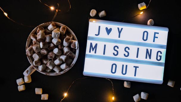 Lightbox con testo JOMO Joy of Missing Out. Il concetto di relax da informazioni e gadget. Vista dall'alto. Piatto. Tazza con cacao e marshmallow. Disintossicazione digitale - Foto, immagini