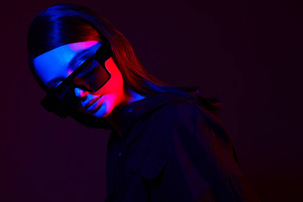 Fashion portrait of young elegant woman in trendy sunglasses. Neon light, studio shot - Photo, image