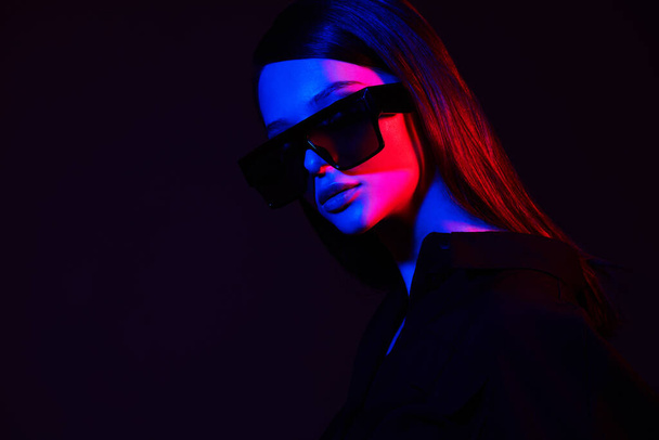 Fashion portrait of young elegant woman in trendy sunglasses. Neon light, studio shot - Foto, afbeelding