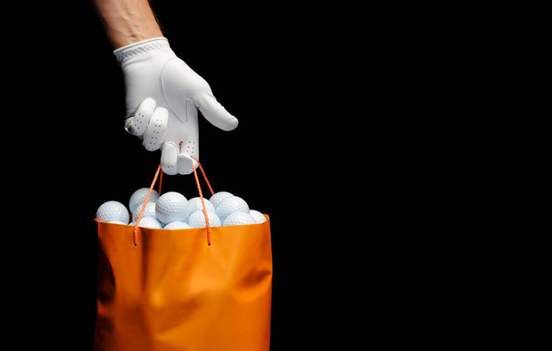 ゴルフボールでいっぱいの袋を保持するゴルフ手袋を身に着けている手のクローズアップ. - 写真・画像