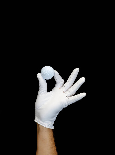 Speler draagt een golfhandschoen met een golfbal in zijn vingers. - Foto, afbeelding
