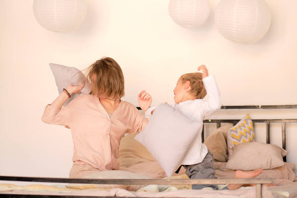 Rodzina walcząca na poduszki w sypialni. Szczęśliwego macierzyństwa. opieka nad dziećmi. - Zdjęcie, obraz