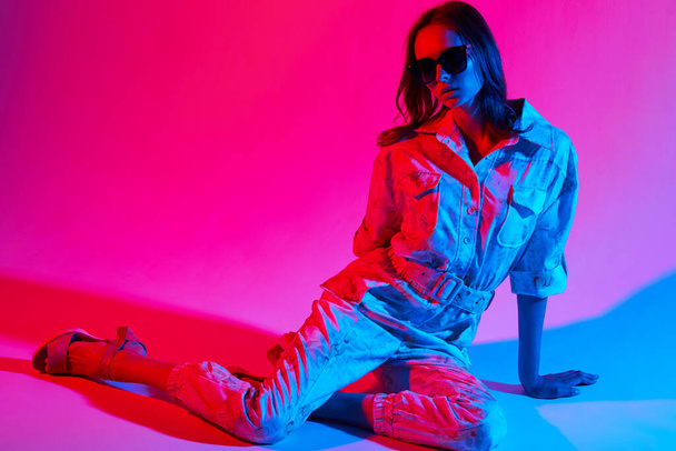 Fashion portrait of young elegant woman wearing overalls. Neon light - Foto, afbeelding