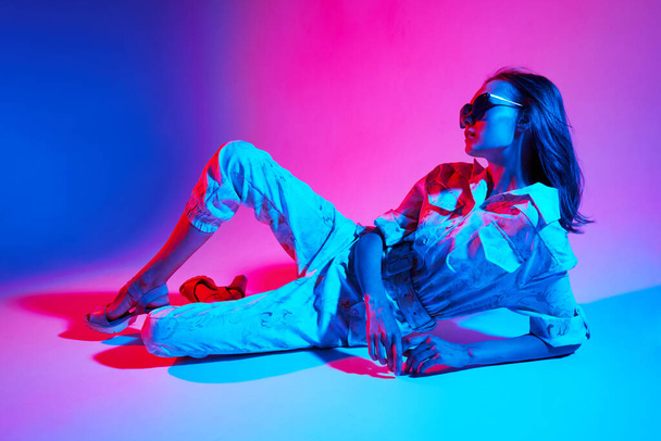 Fashion portrait of young elegant woman wearing overalls. Neon light - Photo, image