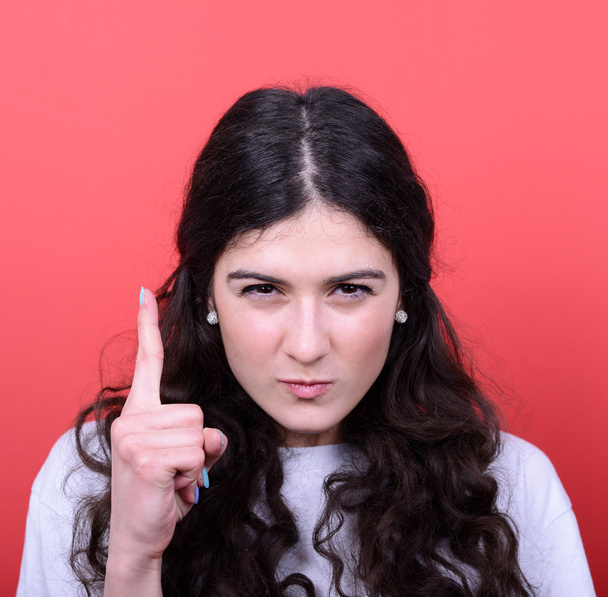 Portrait of woman threatening with finger gesture against red ba - Photo, Image
