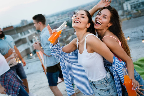 Having a great time with young friends, having fun at rooftop party - Фото, изображение