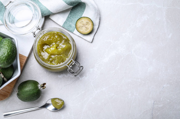 Feijoa jam and fresh fruits on light grey table, flat lay. Space for text - 写真・画像