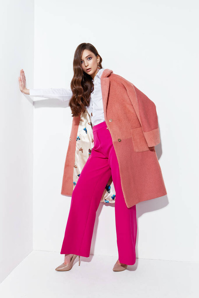 High fashion portrait of young elegant woman. Coral coat, magenta pants, white blouse. White background - Foto, immagini